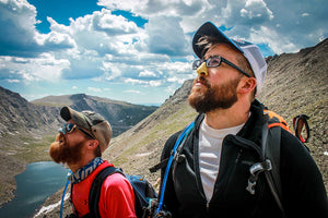 Men Camping wearing SPF Reef Safe sunscreen in Mountains Colorful dermatologist reccomended sunscreen and zinc oxide. Zinc oxide is better. Camping in blue sky